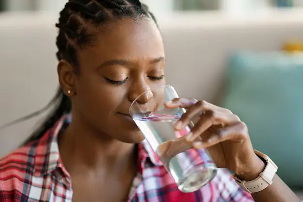 a woman drinking water from a glass