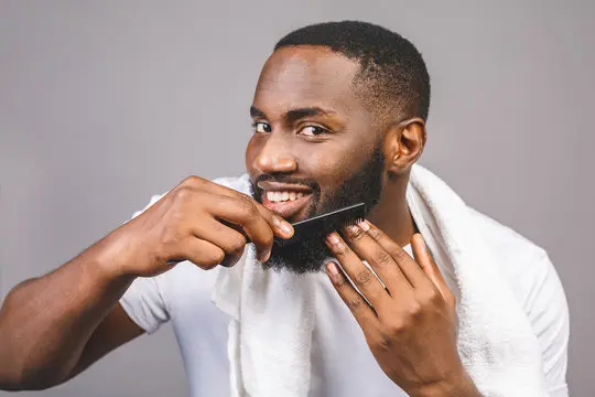 man styling his full beard with a comb