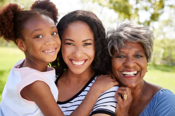 A family with great skin standing next to each other. The daughter is held by the mother, and the wrinkles grandma is on the right side of the picture.