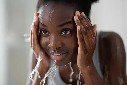 Black washing her face with water to help hydtrate and repair her skin