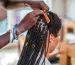 Black woman getting her hair braided.