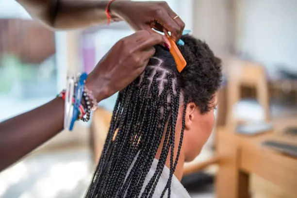 Black woman getting her hair braided.